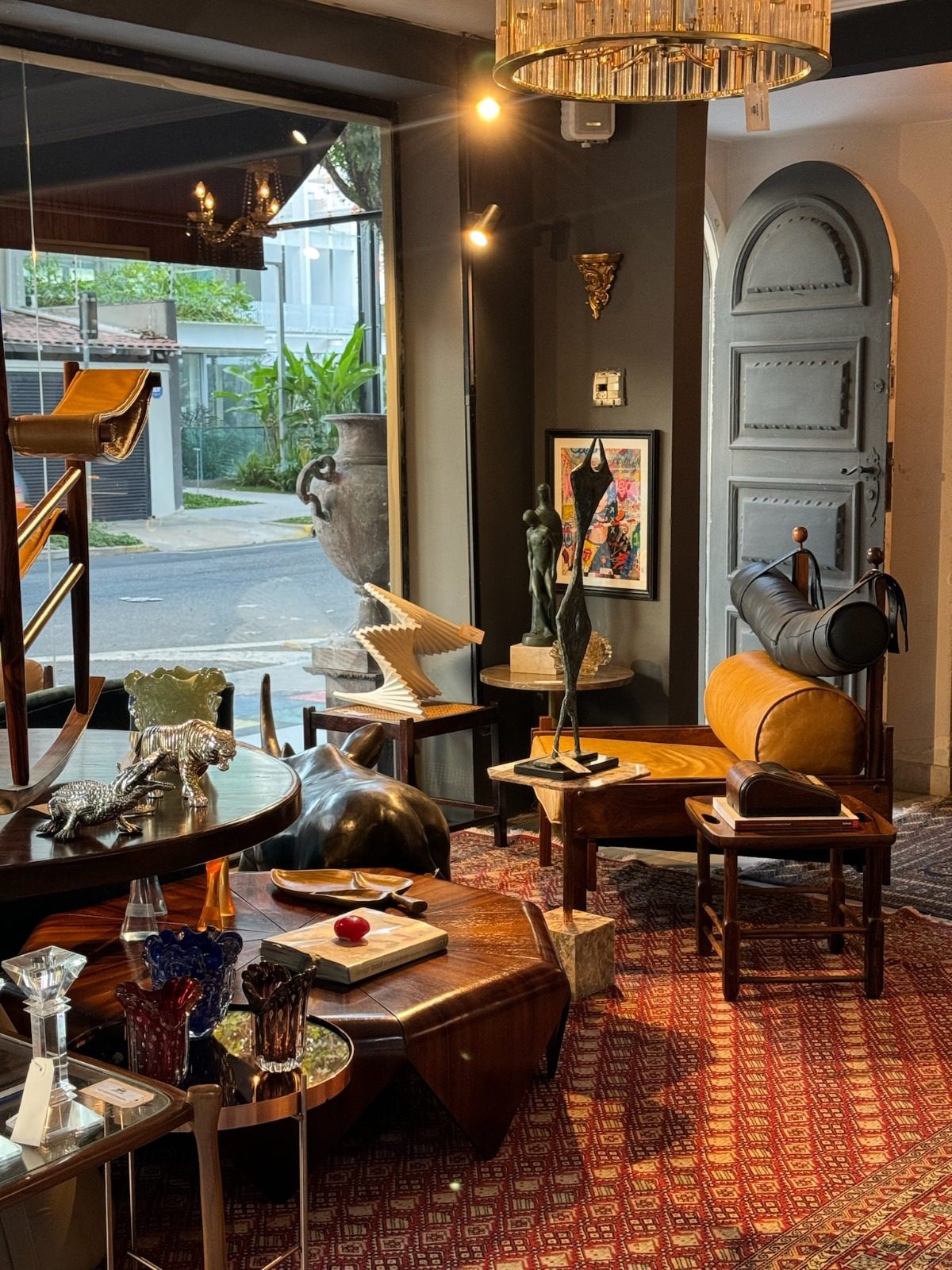 Salão da loja com poltronas de design, esculturas em bronze, lustre de vidro e tapete persa