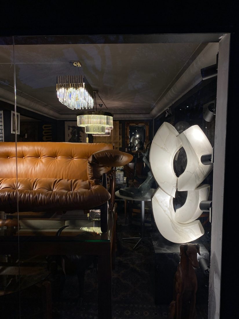 Vitrine iluminada com sofá de couro, lustres de cristal e escultura em mármore