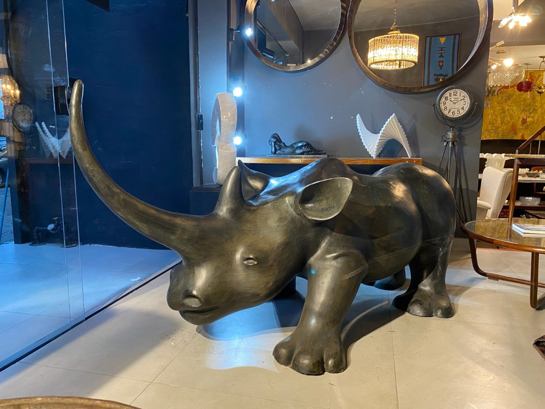 Escultura de rinoceronte em bronze no salão, com espelhos redondos e esculturas ao fundo